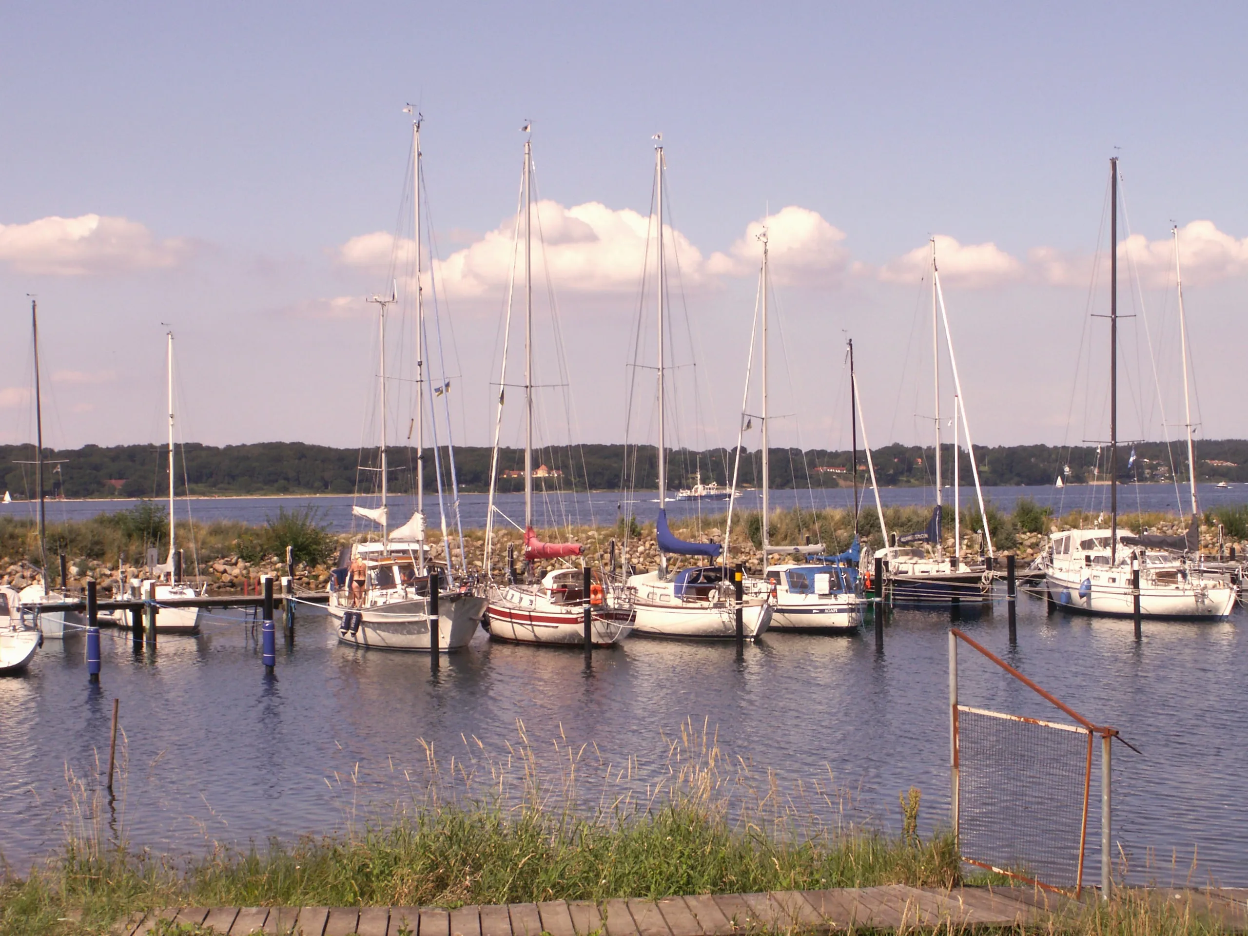 Segelyachten an den Pfählen im Hafen unter Schönwetterwolken